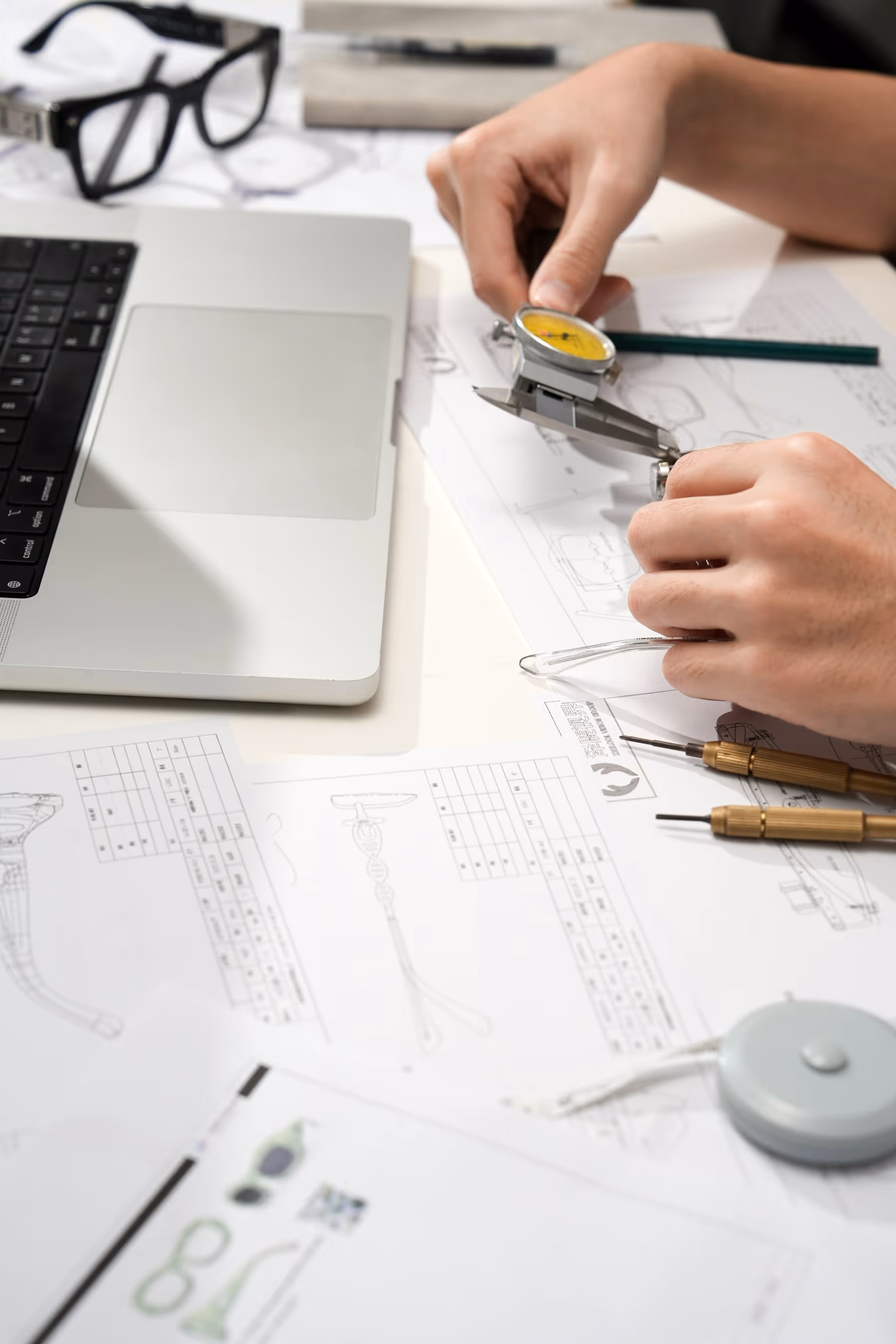 Designer using a dial caliper over technical drawings